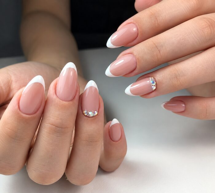 Pink French tips on almond nails with a crystal accent